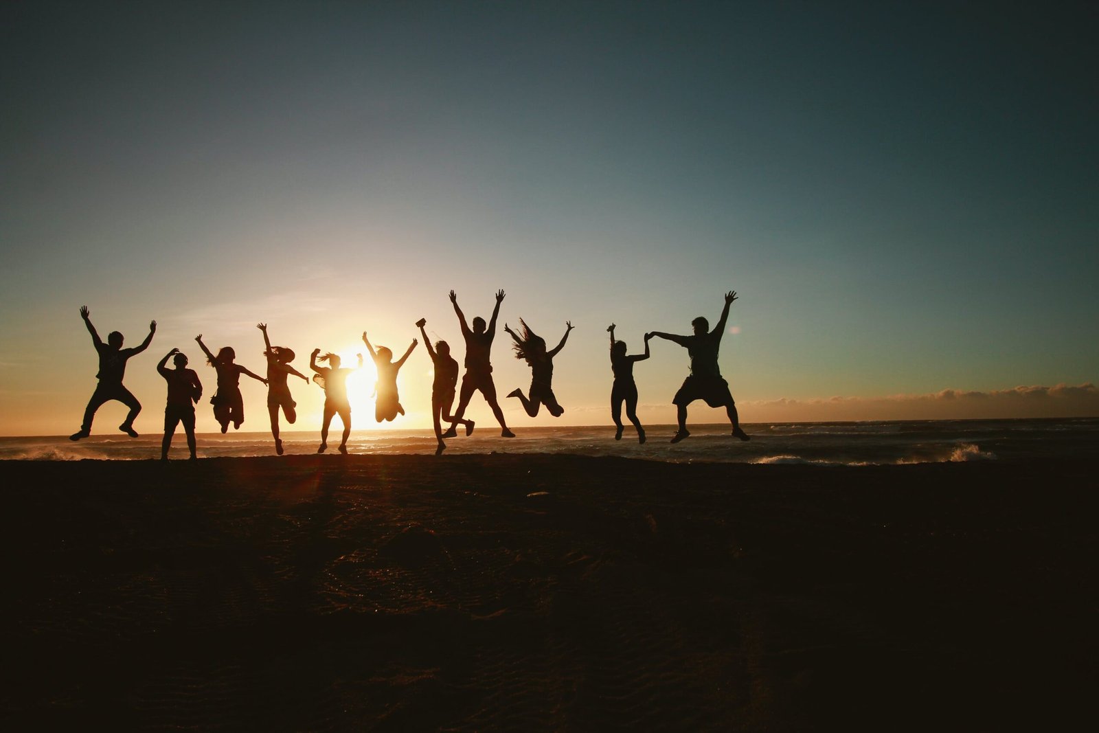 Un groupe de personne sautent face au coucher du soleil