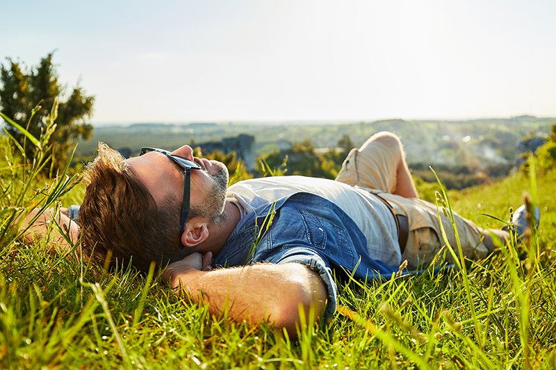 Un homme est allongé dans l’herbe avec des lunettes de soleil