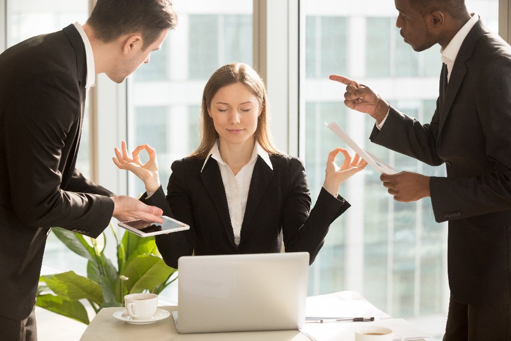 Une femme médite au bureau entouré d’hommes qui lui parle