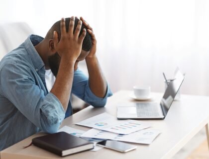 Un homme se tient la tete face à son ordinateur