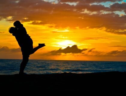 Un couple s’embrasse au bord de la mer avec un coucher de soleil